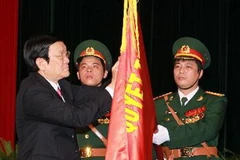 Chủ tịch nước gắn danh hiệu Anh hùng LLVTND lên lá cờ truyền thống của Tổng cục Chính trị-Quân đội nhân dân Việt Nam. (Ảnh: Nguyễn Khang/TTXVN)