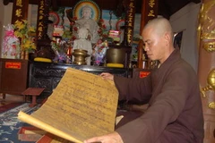 Đại đức Thích Như Tiến - trụ trì chùa Hoa Sơn giới thiệu các sắc phong. (Ảnh: Đoàn Hữu Trung/Vietnam+)