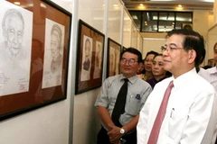 Chủ tịch nước Nguyễn Minh Triết xem các tác phẩm chân dung Mẹ Việt Nam anh hùng tại triển lãm. (Ảnh: Nguyễn Khang/TTXVN).