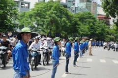 Sinh viên tình nguyện làm rào chắn đảm bảo giao thông cho thí sinh ra về tại trường Đại học Bách Khoa Hà Nội. (Ảnh: Vũ Văn Long/TTXVN)