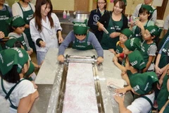 Các em học sinh và phụ huynh đang hoàn thành nốt phong kẹo. (Nguồn: Kyodo) 