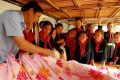 Các em học sinh chăm chú nghe hướng dẫn cách gấp chăn. (Nguồn: Dân Trí)