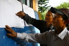 Người dân xem niêm yết danh sách cử tri. (Ảnh: Hồ Cầu/TTXVN)