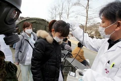 Người dân đang kiểm tra bằng máy đo bức xạ trước khi lên trực thăng. (Ảnh: Cao Phong/Vietnam+) 