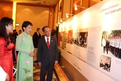 Bà Grace Fu, Bộ trưởng thuộc Văn phòng Thủ tướng Singapore (áo xanh) xem triển lãm ảnh. (Ảnh: Kim Yến/Vietnam+)