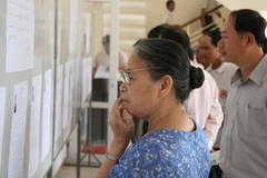 Cử tri xem danh sách niêm yết các đại biểu. (Ảnh: Văn Sơn/TTXVN)