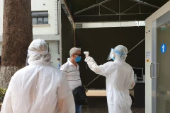 Đo nhiệt độ cho người dân ra vào Bệnh viện Hữu nghị Việt Xô. (Ảnh: T.G/Vietnam+)