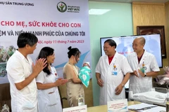 Em bé trong vòng tay của các y bác sỹ và gia đình trong ngày được xuất viện. (Ảnh: T.G/Vietnam+)