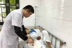 Bác sỹ khám và điều trị cho bệnh nhân bị tai nạn do pháo nổ. (Ảnh: PV/Vietnam+)