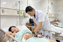 Bác sĩ thăm khám cho người bệnh sau phẫu thuật. (Ảnh: PV/Vietnam+)