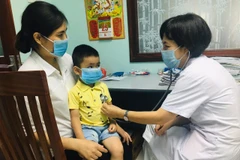 Bác sỹ khám cho bệnh nhi. (Ảnh: PV/Vietnam+)