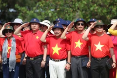 Bà con Kiều bào cùng các đại biểu làm lễ chào cờ tại đảo Trường Sa. (Ảnh: Hồng Sơn/Vietnam+)