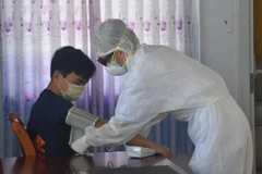 Nhân viên y tế kiểm tra sức khoẻ cho người được cách ly phòng bệnh COVID-19. (Ảnh: Hoàng Nhị/TTXVN)