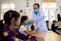 Cán bộ y tế phát khẩu trang cho các em học sinh tại Trường Phổ thông dân tộc bán trú Tiểu học xã Khâu Vai (Mèo Vạc, Hà Giang). (Ảnh: Nam Thái/TTXVN)