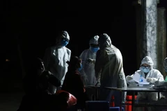 Kiểm tra thân nhiệt người dân đưa về tại khu cách ly. (Ảnh: Phan Tuấn Anh/TTXVN)