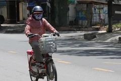 Người tham gia giao thông phải mặc đồ bảo hộ kín người, để tránh nắng nóng. (Ảnh: Nguyên Lý/TTXVN)