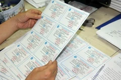 Kiểm tra thẻ bảo hiểm y tế trước khi phát cho người dân. (Ảnh: PV/Vietnam+)