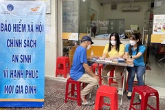 Nhân viên bảo hiểm xã hội tư vấn về chính sách bảo hiểm xã hội, bảo hiểm y tế cho người dân. (Ảnh: TTXVN/Vietnam+)