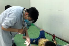 Bác sỹ thăm khám cho trẻ mắc bệnh tay chân miệng. (Ảnh: TTXVN/Vietnam+)