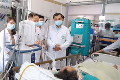 Thứ trưởng Bộ Y tế Trần Văn Thuấn thăm nạn nhân nặng nhất của vụ cháy nhà trọ đang điều trị tại Trung tâm Hồi sức, Bệnh viện Bạch Mai. (Ảnh: PV/Vietnam+)