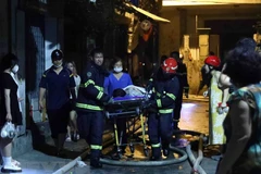 Lực lượng chức năng đưa các nạn nhân ra khỏi vụ cháy. (Ảnh: Phạm Kiên/TTXVN)