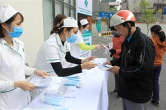 Phát khẩu trang miễn phí cho người dân tại Bệnh viện Đa khoa tỉnh Thái Bình. (Ảnh: Thế Duyệt/TTXVN)