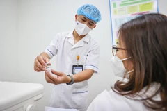 Nhân viên y tế hướng dẫn người dân trước khi tiêm vaccine. (Ảnh: PV/Vietnam+)