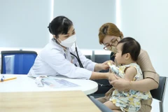 Nhân viên y tế khám cho trẻ trước khi tiêm chủng. (Ảnh: Minh Quyết/TTXVN)