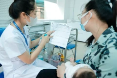 Nhân viên y tế hướng dẫn người dân về vaccine trước khi tiêm cho trẻ. (Ảnh: Minh Quyết/TTXVN) 