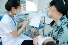 Nhân viên y tế hướng dẫn người dân về vaccine trước khi tiêm cho trẻ. (Ảnh: Minh Quyết/TTXVN) 