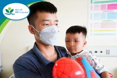 Bé trai và bố trong ngày xuất viện. (Ảnh: PV/Vietnam+)