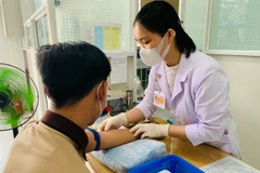 Nhân viên y tế tại Trung tâm Y tế thành phố Long Xuyên lấy máu xét nghiệm HIV cho người dân. (Ảnh: PV/Vietnam+)