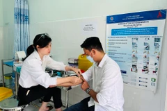 Nhân viên y tế Trung tâm Kiểm soát bệnh tật tỉnh Kiên Giang lấy mẫu xét nghiệm theo dõi điều trị HIV cho một bệnh nhân. (Ảnh: T.G/Vietnam+)