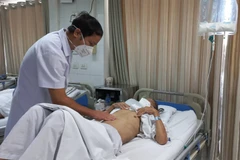 Phó giáo sư Phạm Hoàng Hà thăm khám cho một bệnh nhân ung thư dạ dày. (Ảnh: PV/Vietnam+)