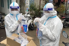 Cán bộ y tế chuẩn bị túi thuốc an sinh để trao cho F0 đang điều trị tại nhà. (Ảnh: Tường Quân/TTXVN)