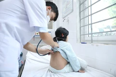 Bác sỹ kiểm tra phổi cho một bệnh nhi. (Ảnh: PV/Vietnam+)