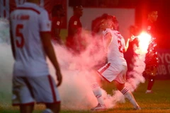 Một quả pháo sáng được ném thẳng xuống sân, buộc cầu thủ Sông Lam Nghệ An phải ném pháo ngược ra ngoài đường pít cho trận đấu tiếp tục diễn ra. (Ảnh: Minh Chiến/Vietnam+)