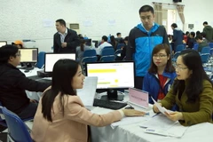 Nhân viên Cục Thuế Hà Nội hướng dẫn người nộp thuế nộp quyết toán thuế. (Ảnh: Hoàng Hùng/TTXVN)