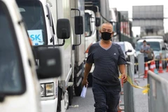 Nhiều chủ xe xếp hàng dài để chờ kiểm tra, kiểm soát các điều kiện bắt buộc mới qua được chốt kiểm dịch. (Ảnh: TTXVN)
