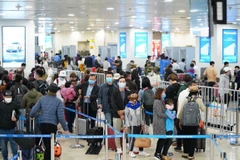 Hành khách tuân thủ việc đeo khẩu trang khi làm thủ tục chuyến bay tại Cảng hàng không quốc tế Nội Bài. (Ảnh: Phan Công/Vietnam+)