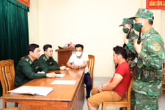 Lực lượng biên phòng lấy lời khai hai đối tượng. (Ảnh TTXVN phát)