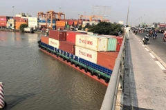Tàu Phước Long 72 chở container số hiệu SG9838 trọng tải 4.600 tấn bị mắc kẹt dưới cầu Đồng Nai sáng 12/4, trước khi được cứu hộ và lai dắt đến nơi an toàn. (Ảnh: TTXVN phát)