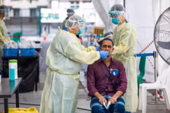 Nhân viên y tế lấy mẫu xét nghiệm COVID-19 cho người dân tại Singapore hồi năm ngoái. (Ảnh: AFP/TTXVN)