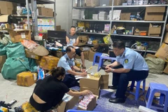 Cán bộ Đội Quản lý Thị trường số 1 kiểm tra sản phẩm bút bi có dấu hiệu giả mạo nhãn hiệu. (Ảnh: PV/Vietnam+)