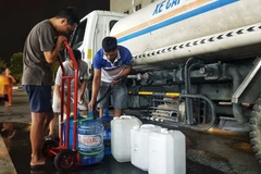 Người dân Khu Đô thị Thanh Hà lấy nước từ xe chở nước sạch. (Ảnh: Hoàng Hiếu/TTXVN)