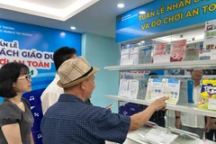 Hướng dẫn người tiêu dùng phân biệt hàng giả tại phòng trưng bày của Tổng cục Quản lý Thị trường. (Ảnh: Đức Duy/Vietnam+) 