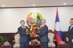 Đại sứ Nguyễn Minh Tâm tặng hoa chúc mừng 49 năm Quốc khánh Lào cho Bộ trưởng Bộ Ngoại giao Lào Thongsavanh Phomvihane. (Ảnh: Xuân Tú/TTXVN)