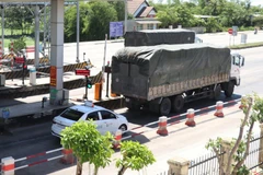 Xe ôtô con bám sát xe phía trước để vượt trạm, khi thanh barie chưa kịp đóng lại. (Ảnh: Nguyên Lý/TTXVN)