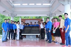 Đoàn hành trình "Về nguồn" chụp ảnh kỷ niệm tại khu nhà bia lưu niệm nơi làm việc của Việt Nam Thông tấn xã ở An toàn khu Sơn Dương, Tuyên Quang. (Ảnh: Minh Sơn/Vietnam+)