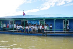 Các em học sinh kiều bào tại ngôi trường nổi tiễn chào đoàn công tác. (Nguyễn Lâm/Vietnam+)